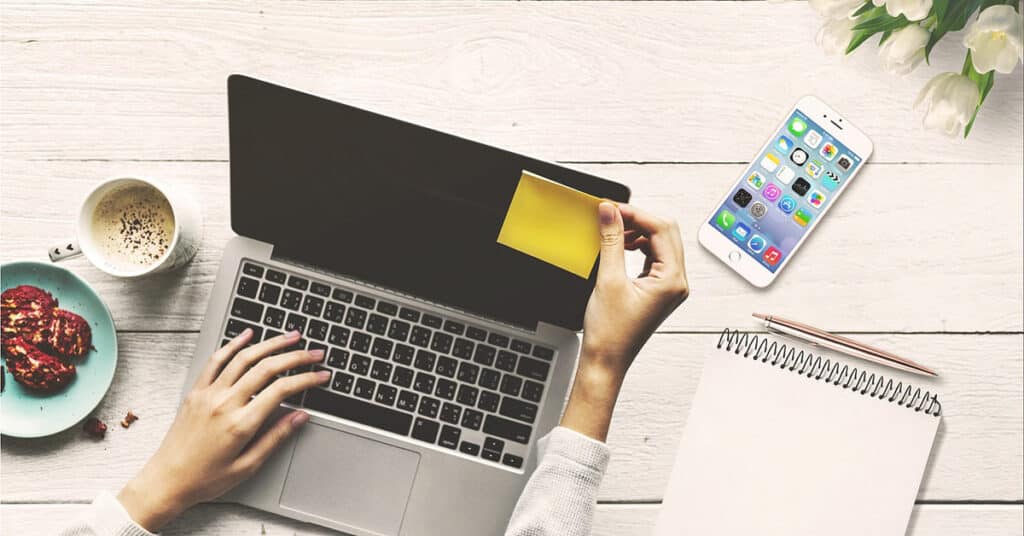 Worker putting Post-It on laptop